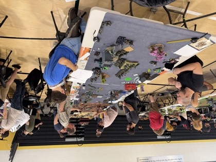 Players lean over a battlefield mid-game