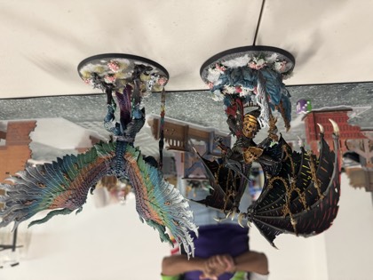 Two winged daemon centrepiece models face off on the table