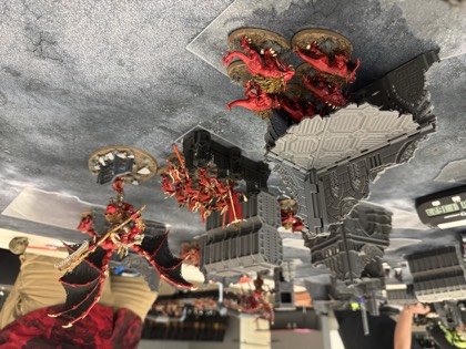 Red-armoured daemons swarm a ruin